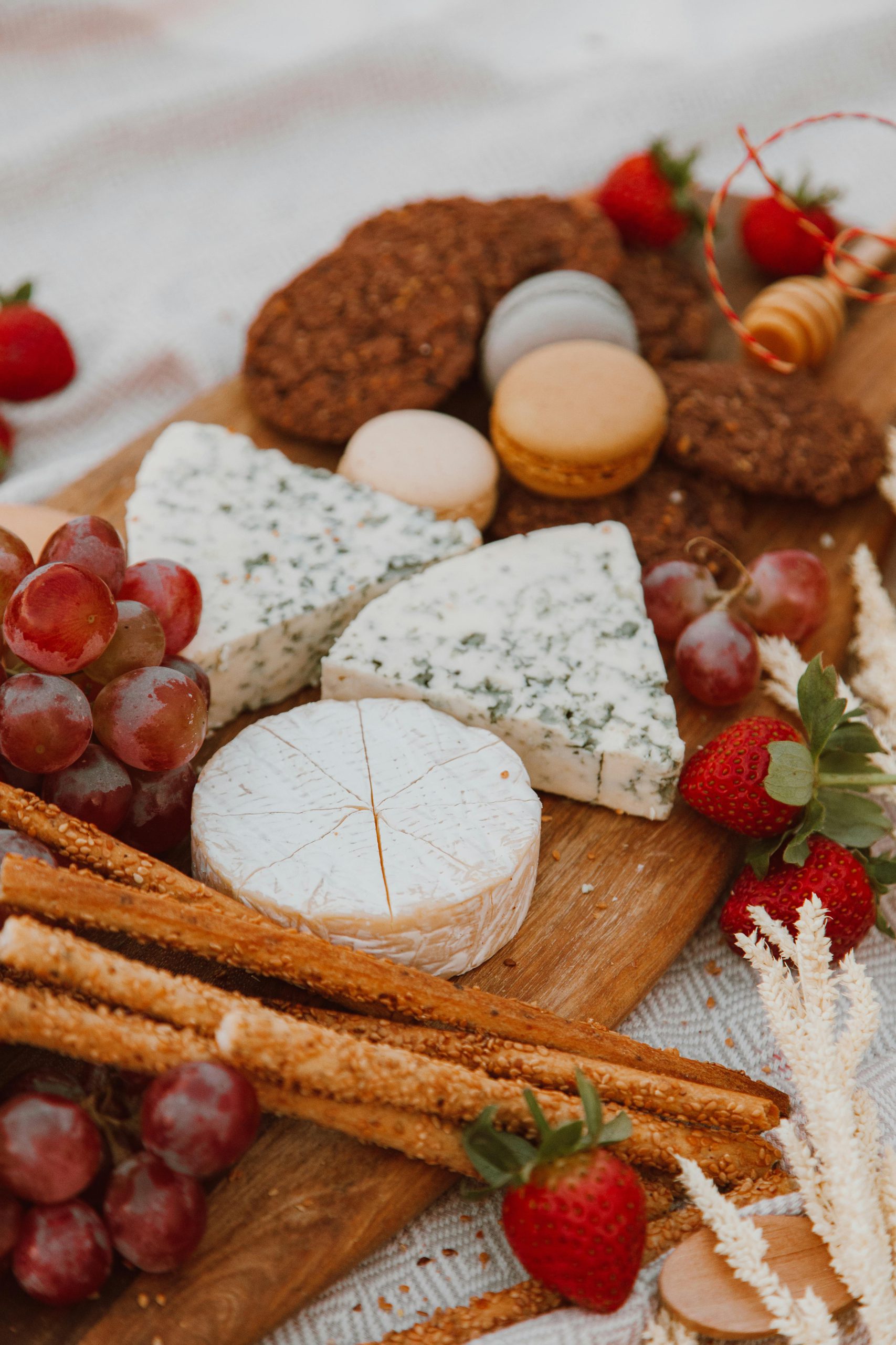 Artistic display of cheese, fruits, and desserts on a wooden board, perfect for elegant gatherings.